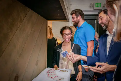 a black color womane wering shurg Adam Stone is showing cards magic