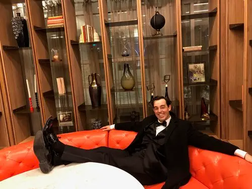 Adam Stone sits on a red sofa and poses for a photo